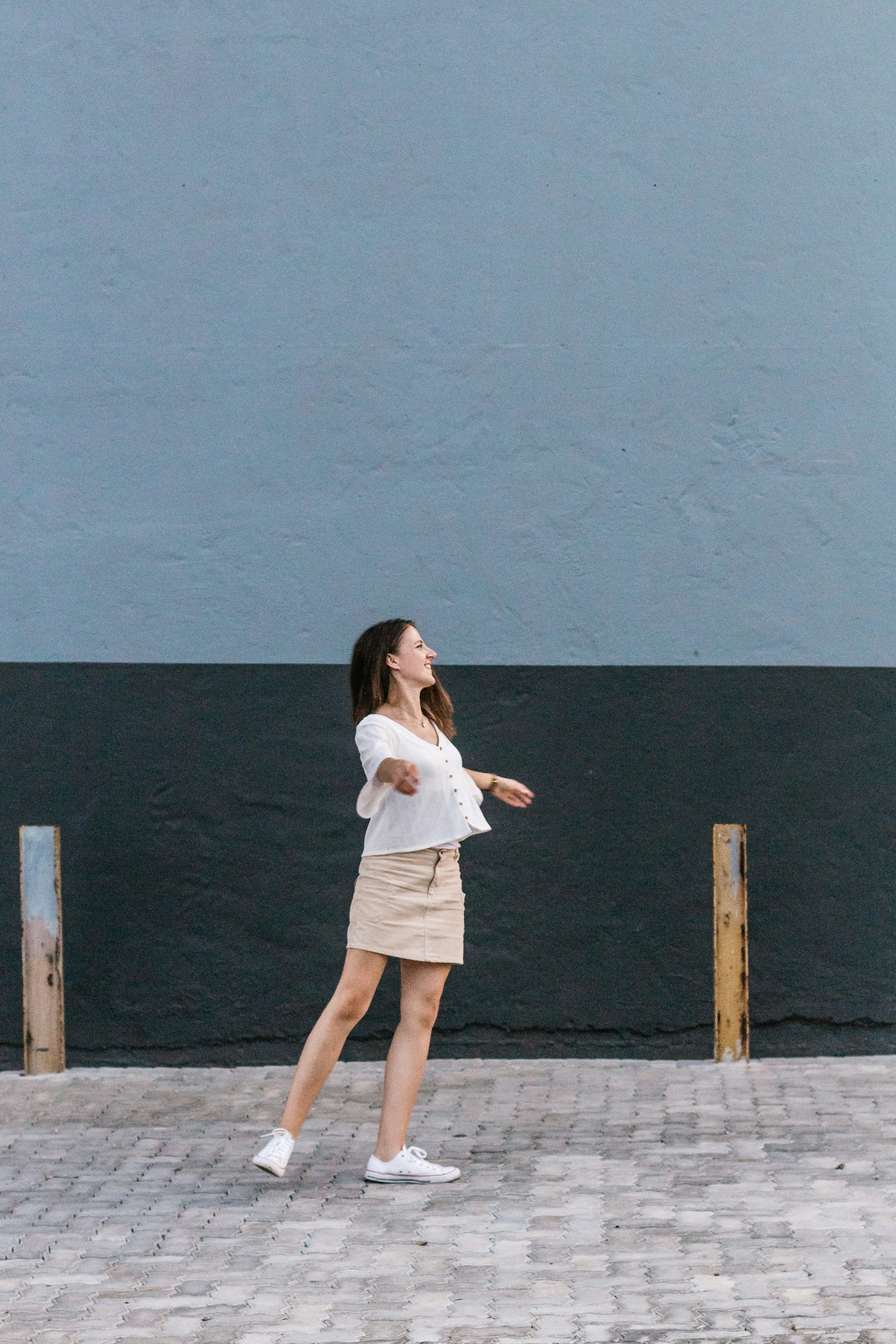 woman in white shirt and skirt standing beside wall